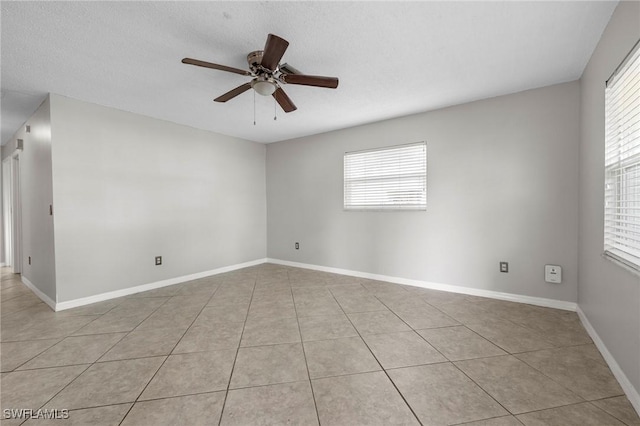 unfurnished room featuring light tile patterned floors, a ceiling fan, baseboards, and a textured ceiling