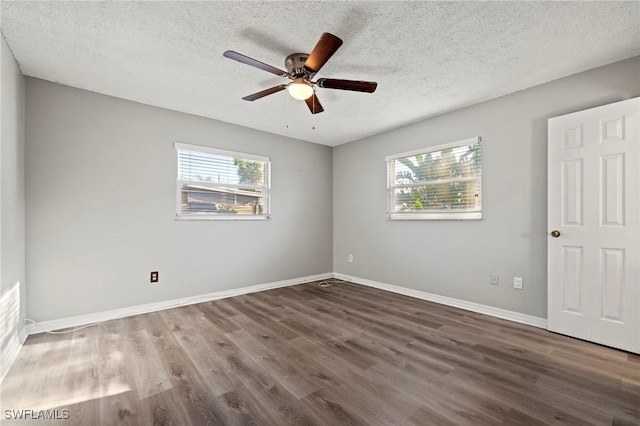 spare room featuring a textured ceiling, baseboards, and wood finished floors