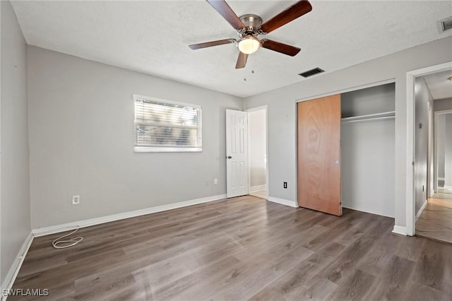 unfurnished bedroom with visible vents, a textured ceiling, baseboards, and wood finished floors