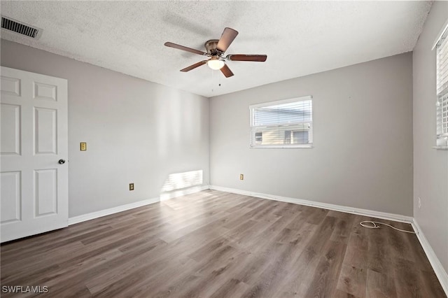 empty room featuring visible vents, baseboards, wood finished floors, a textured ceiling, and a ceiling fan