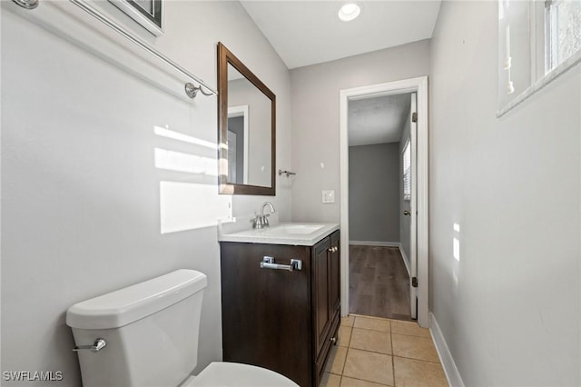 bathroom featuring baseboards, toilet, vanity, and tile patterned flooring