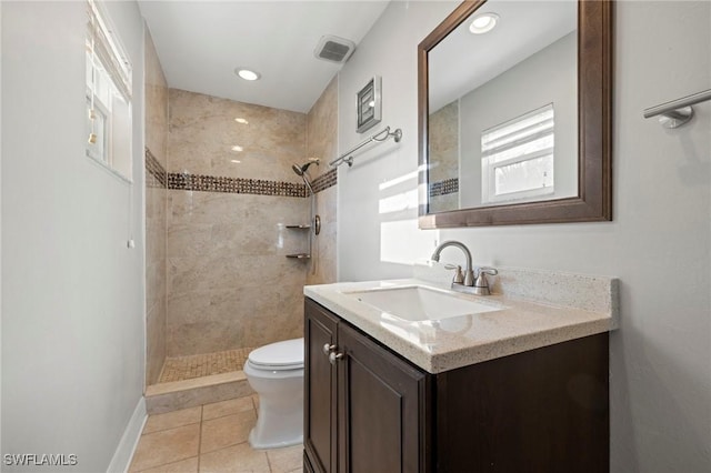 bathroom featuring tile patterned floors, toilet, a tile shower, baseboards, and vanity