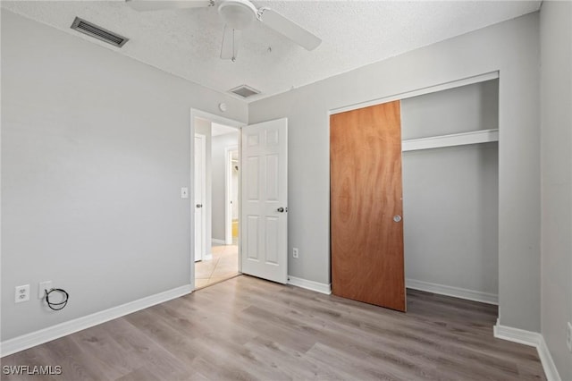 unfurnished bedroom with wood finished floors, baseboards, visible vents, a closet, and a textured ceiling