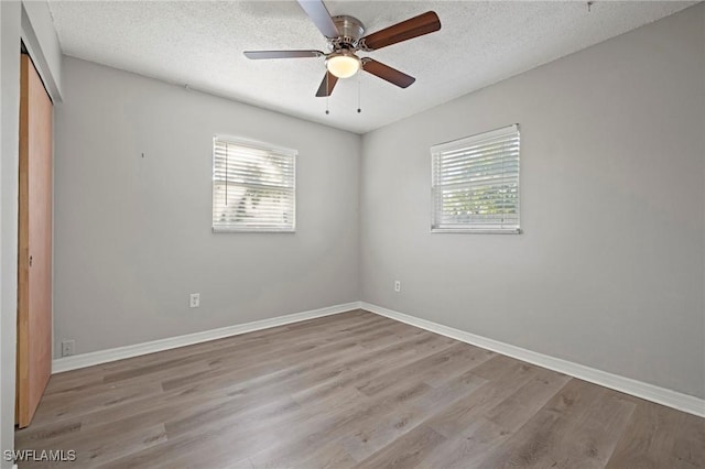 unfurnished bedroom with multiple windows, a textured ceiling, and wood finished floors