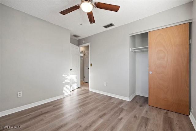 unfurnished bedroom with visible vents, baseboards, a closet, and wood finished floors