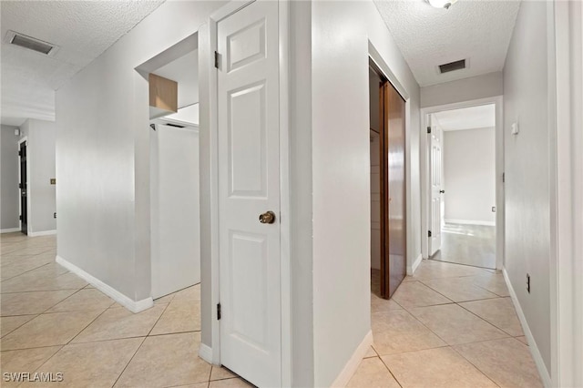 corridor with light tile patterned floors, visible vents, and a textured ceiling