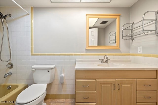 full bathroom with toilet, tile walls, wainscoting, tub / shower combination, and vanity