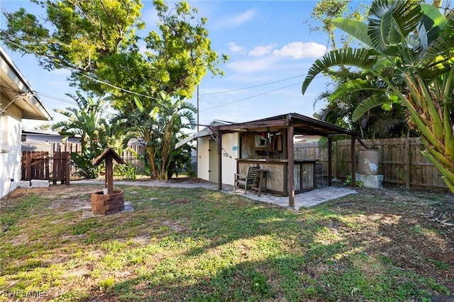 view of yard with a patio area, a fenced backyard, and outdoor dry bar