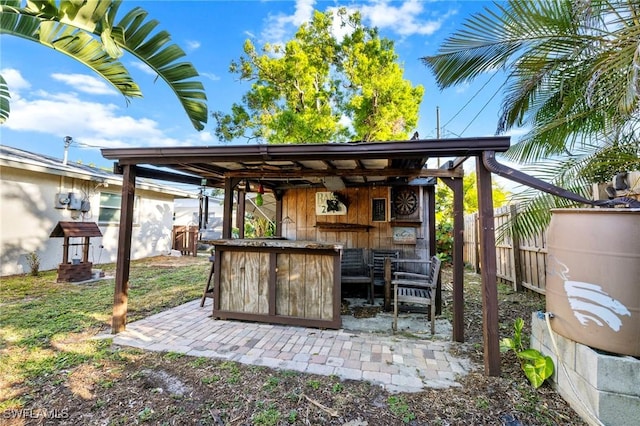 view of patio featuring outdoor dry bar and fence