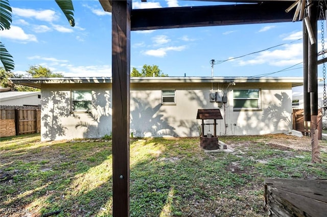 view of side of property with stucco siding, a yard, and fence