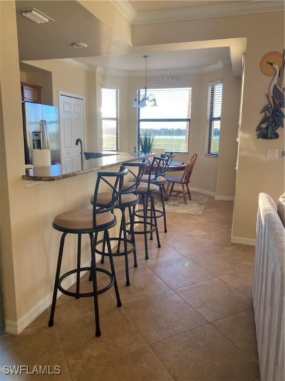 dining area featuring tile patterned floors, baseboards, visible vents, and ornamental molding