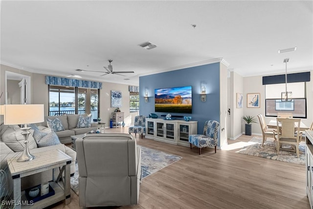 living room featuring visible vents, light wood-style floors, ceiling fan, and ornamental molding