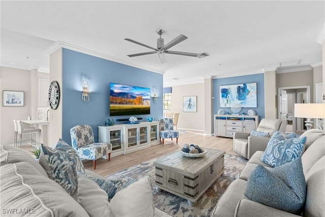 living room with visible vents, baseboards, light wood-type flooring, ornamental molding, and a ceiling fan