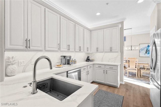 kitchen with light wood-type flooring, light stone counters, appliances with stainless steel finishes, white cabinets, and a sink