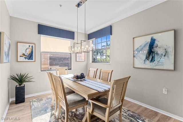 dining space featuring a notable chandelier, light wood-style floors, baseboards, and ornamental molding