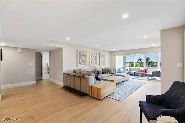 living area with recessed lighting, baseboards, and light wood-style flooring