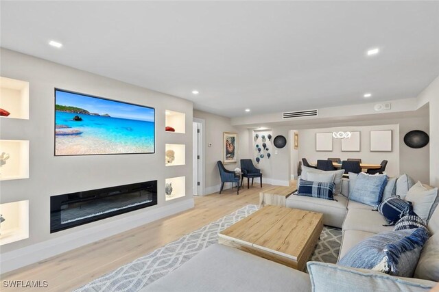 living room featuring wood finished floors, visible vents, baseboards, recessed lighting, and a glass covered fireplace