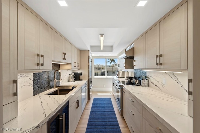 kitchen with light stone countertops, stainless steel appliances, backsplash, and a sink