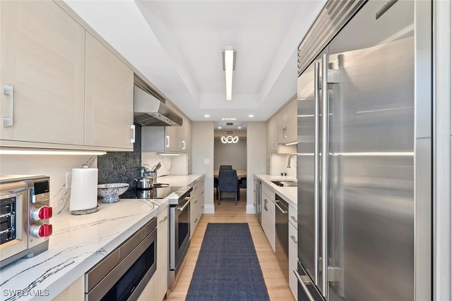 kitchen with tasteful backsplash, extractor fan, appliances with stainless steel finishes, modern cabinets, and a sink