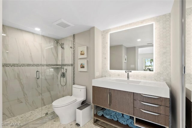 bathroom featuring visible vents, toilet, marble finish floor, a marble finish shower, and vanity