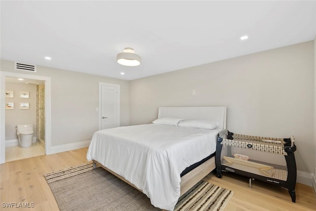 bedroom with ensuite bath, light wood-style flooring, visible vents, and baseboards