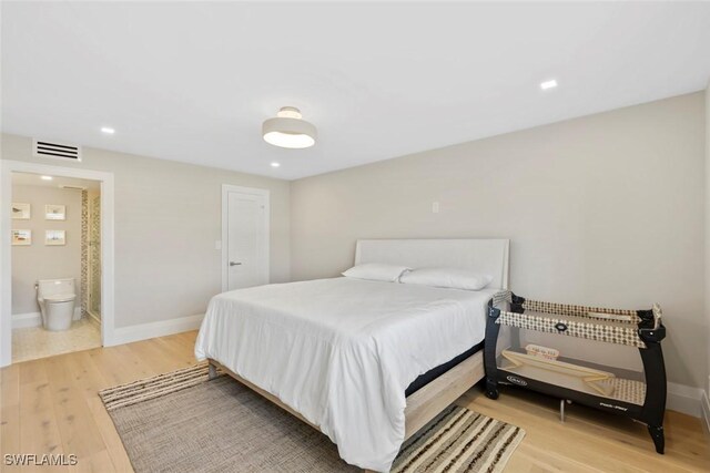 bedroom with visible vents, baseboards, light wood-style flooring, and ensuite bathroom