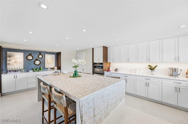 kitchen with tasteful backsplash, a kitchen island, light countertops, recessed lighting, and white cabinetry