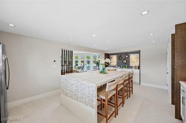 kitchen with recessed lighting, baseboards, marble finish floor, and freestanding refrigerator