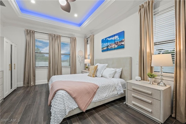 bedroom with a raised ceiling, wood finish floors, and ornamental molding