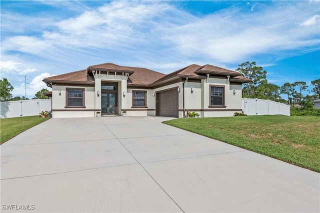 prairie-style house featuring driveway, a front yard, an attached garage, and a gate