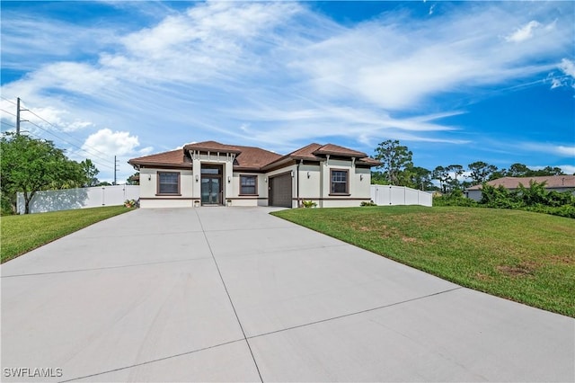 prairie-style house with a front yard, fence, a garage, and driveway