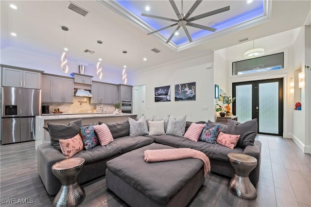 living area featuring visible vents, ceiling fan, crown molding, and light wood-style flooring