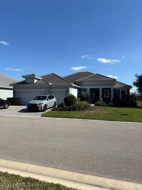 view of front of home with an attached garage, driveway, and a front lawn