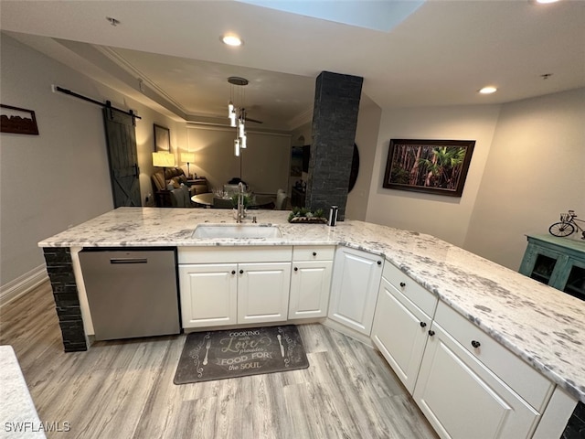 kitchen featuring light wood-style flooring, a sink, white cabinets, dishwasher, and a barn door