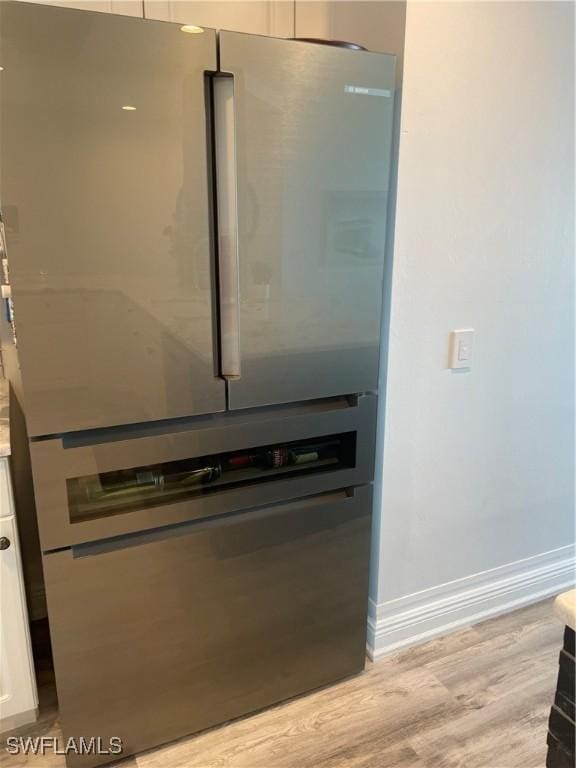 room details featuring baseboards, freestanding refrigerator, light countertops, white cabinets, and light wood-style floors