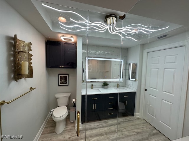 bathroom featuring a sink, visible vents, toilet, and wood finished floors