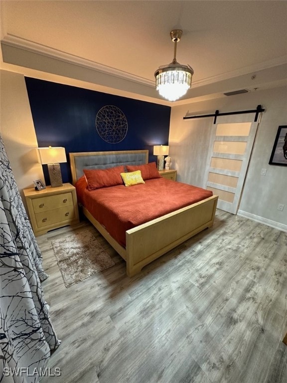 bedroom with baseboards, a barn door, and wood finished floors