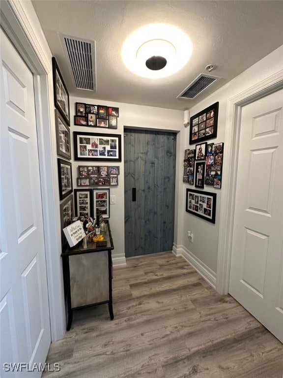 hallway featuring visible vents, baseboards, and wood finished floors