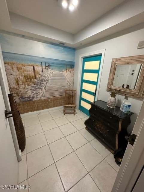 entrance foyer featuring a view of the beach, light tile patterned flooring, visible vents, and a water view