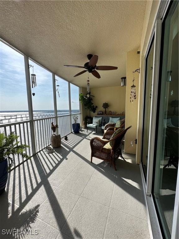 exterior space with ceiling fan, a balcony, and a water view