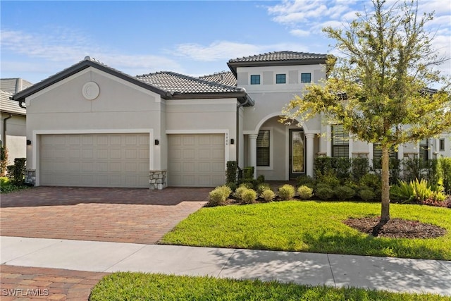 mediterranean / spanish-style home with decorative driveway, a garage, a front yard, and stucco siding