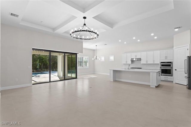 unfurnished living room with baseboards, visible vents, coffered ceiling, and a chandelier