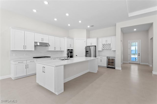 kitchen featuring beverage cooler, under cabinet range hood, white cabinetry, stainless steel fridge with ice dispenser, and black cooktop