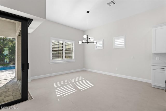 unfurnished dining area featuring an inviting chandelier, baseboards, and visible vents