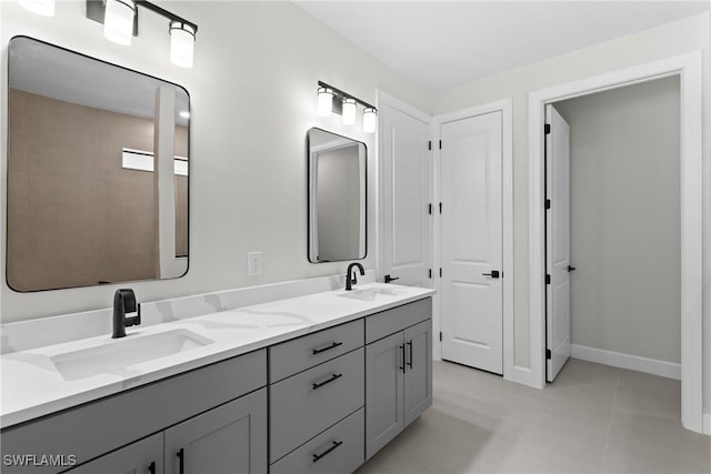 full bath featuring double vanity, tile patterned flooring, baseboards, and a sink