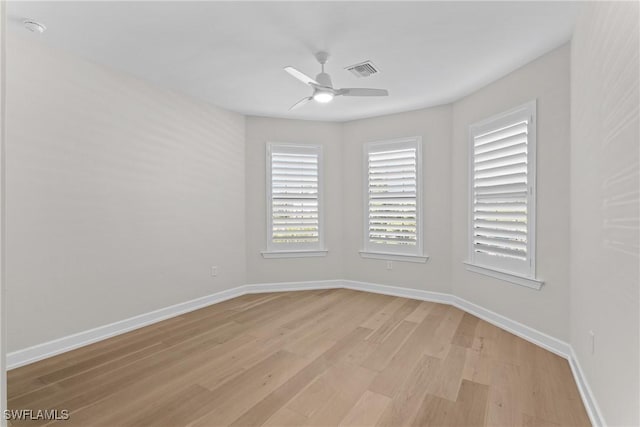 empty room featuring light wood-style floors, a ceiling fan, visible vents, and baseboards