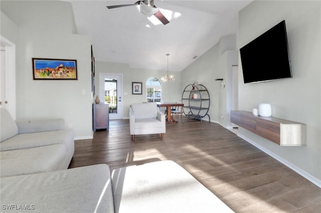 living room featuring ceiling fan with notable chandelier, high vaulted ceiling, baseboards, and wood finished floors