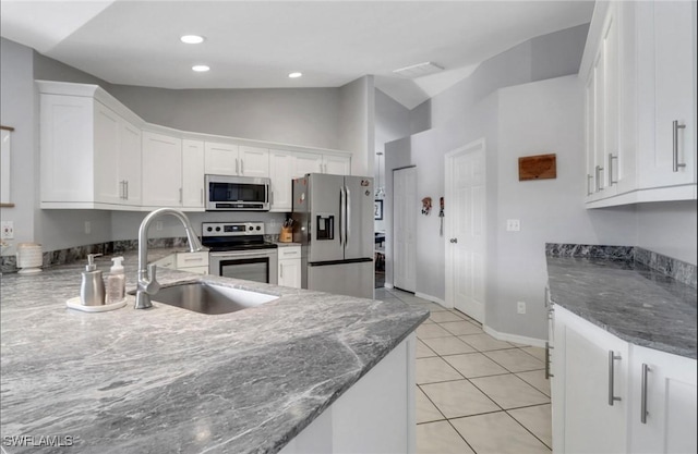 kitchen with a sink, lofted ceiling, appliances with stainless steel finishes, and white cabinetry