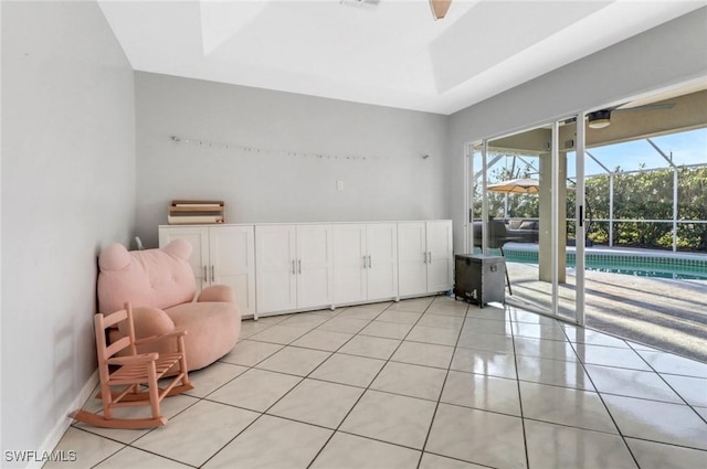 sitting room with a raised ceiling, a healthy amount of sunlight, light tile patterned flooring, and a sunroom