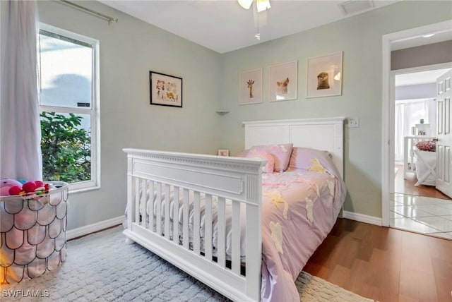 bedroom featuring visible vents, multiple windows, wood finished floors, and baseboards